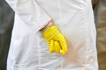 白色浴袍和黄色手套一只手放在背后的女孩不适合的医务工作图片