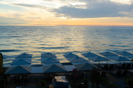日出时海上的沙滩伞躺椅图片