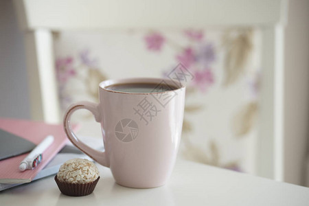 白桌背景上带糖果的粉色茶杯图片