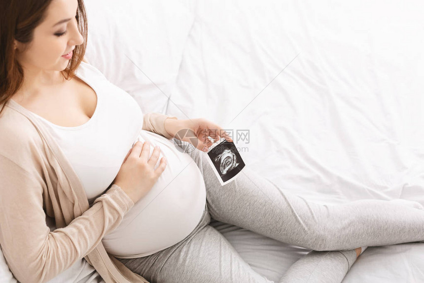 享受孕期的年轻女与婴儿超声波照片图片