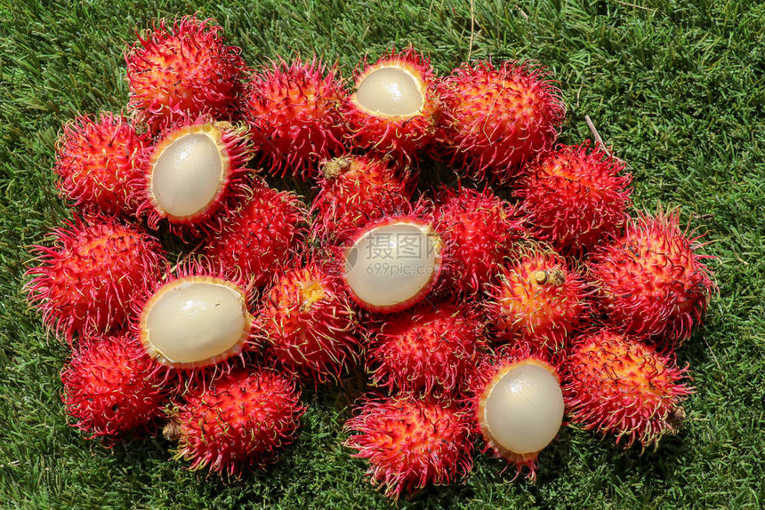 关闭去皮的红毛丹顶视图绿色草坪上的健康水果准备吃甜巴厘岛水果实是圆形的椭圆形单种子浆果图片