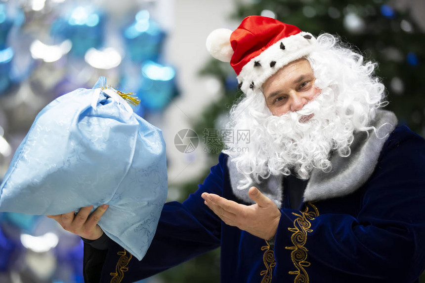 圣诞老人指着一个带礼物的袋子图片