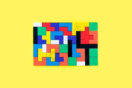黄色背景上不同形状的彩色木块拼图天然环保玩具创意逻辑思维概念背景与几图片