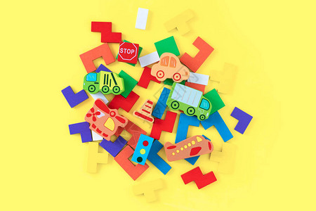 黄色背景上的彩色发展木块和手工汽车天然环保的儿童木制玩具顶视图平图片
