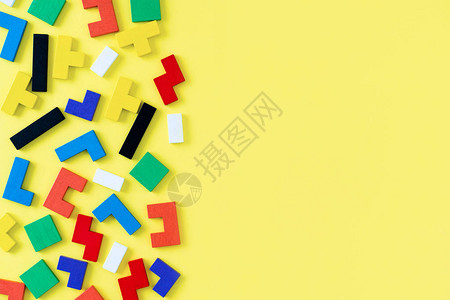 黄色背景上不同形状的彩色木块拼图天然的儿童玩具创意逻辑思维概念平图片
