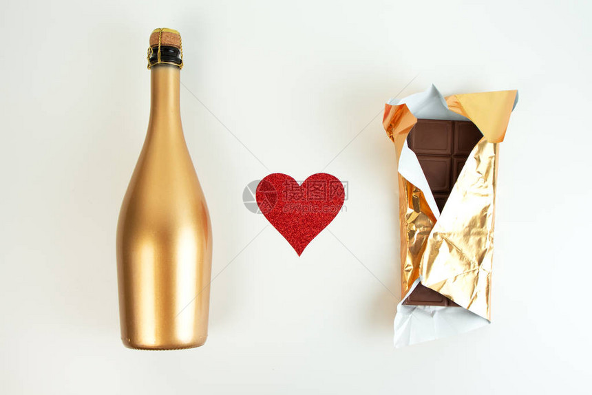 金香槟酒瓶和巧克力棒装在金包装纸上红光心放在白色背图片