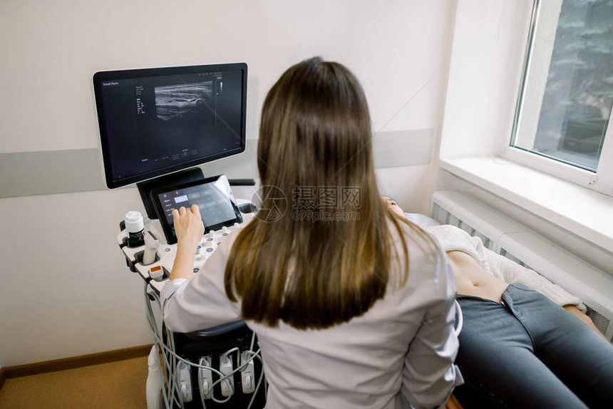 年轻女医生准备对女患者进行腹部超声检查的背影医生在开始超声检查程序之前按下控制图片