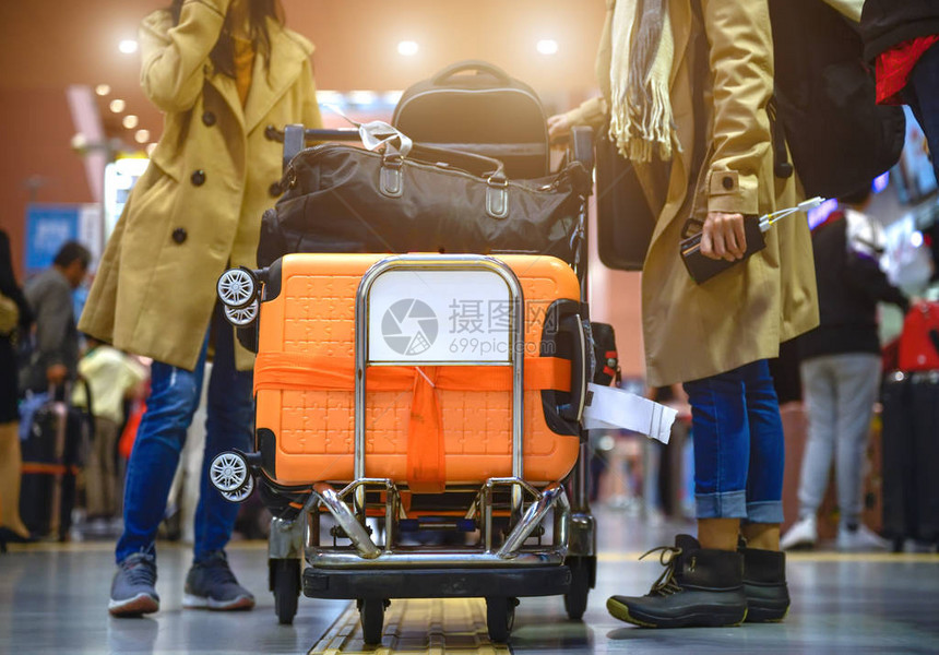 许多行李由女旅客在机场提手的推车中携带图片