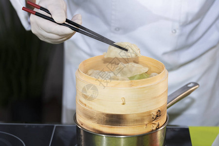 一个厨师要用筷子把一个子放到竹船里亚洲食品概念图片