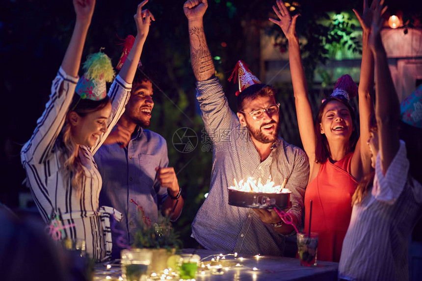 一群在夜总会开生日派对的年轻朋友晚上带着蛋糕和蜡烛图片