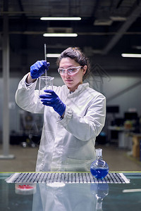 身戴眼镜和白大衣手握有实验玻璃的重度实验室女孩图片