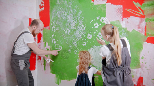 幸福的家庭正在将他们的白色手印放在绿色的墙上图片