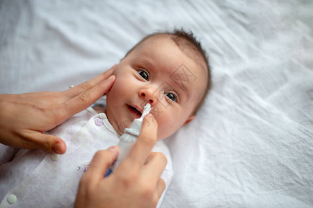为婴儿使用鼻喷雾剂的妇女图片
