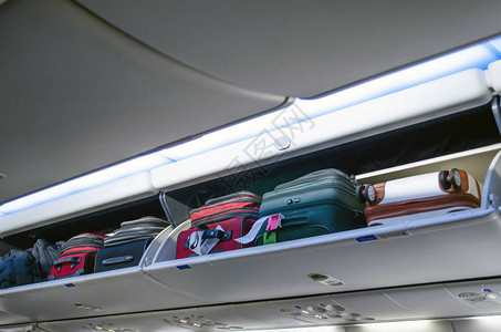 飞机上装满随身行李和行李的头顶行李箱图片