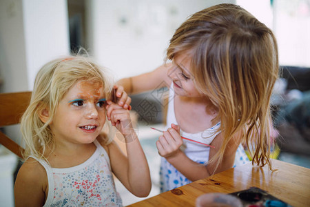 两姐妹在家里玩脸颜料年长女孩在小妹脸上图片