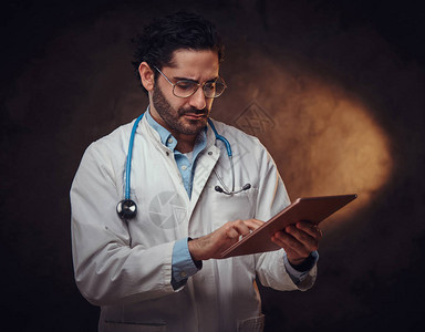 认真的临床医生在寻找平板电脑时仔细思考病人诊断问图片