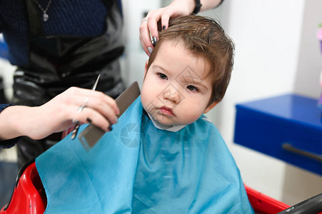 美发师特写镜头的孩子孩子在理发店的第一次理发婴儿图片