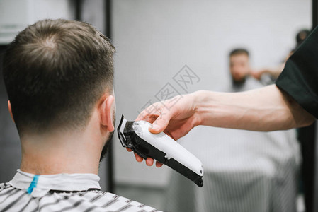 理发师的手用剪刀断了一个男人的后颈在理发店理发理发师刮胡子一个年轻人理发剪男士美容院的男士理发背背景图片