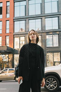 穿着时尚黑色衣服的迷人女士站在现代大都市的背景下图片