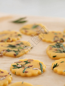 特写烘焙纸上带有香草种子和帕尔马干酪的新鲜饼干制作饼干的过程家图片
