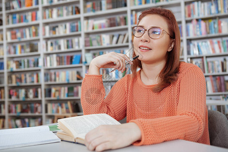 迷人的年轻女子在大学图书馆读书时微笑图片