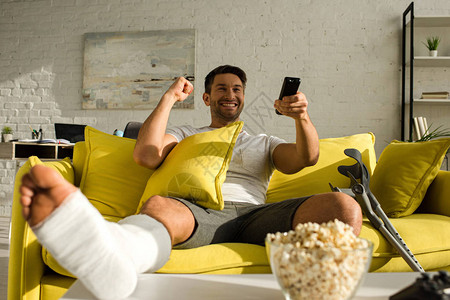 有选择焦点快乐的男人断腿看电视在起居室桌子上背景图片