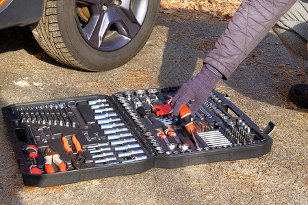 汽车司机使用不同的修理工具修理汽车橙色汽车附近的工具集框中机械工图片