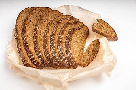 Rye面包被撕成碎片躺在烘烤纸上白底的白色面图片