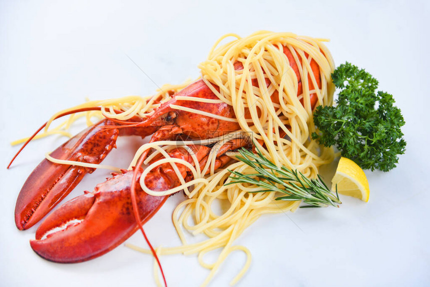 白盘上的意大利面海鲜龙虾食品与香草料柠檬迷迭香在餐厅的餐桌上供应健康水煮龙虾熟沙拉图片