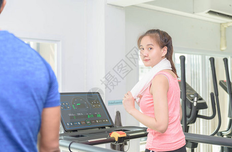漂亮的亚洲女孩在体育馆的跑步机里工作图片