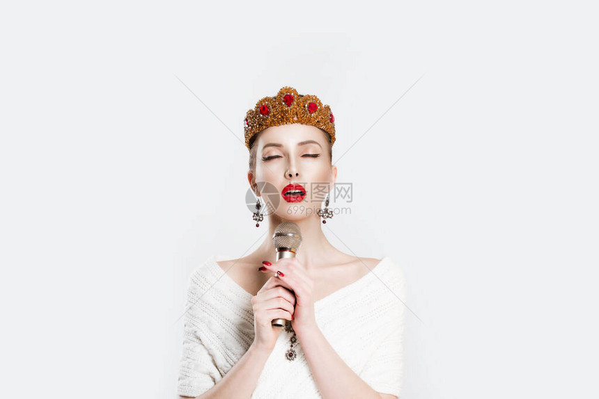 复古歌手选美皇后在麦克风上说唱卡拉ok孤立的白色背景墙带着金色红宝石皇冠首饰红唇完美妆容的愤怒女孩图片
