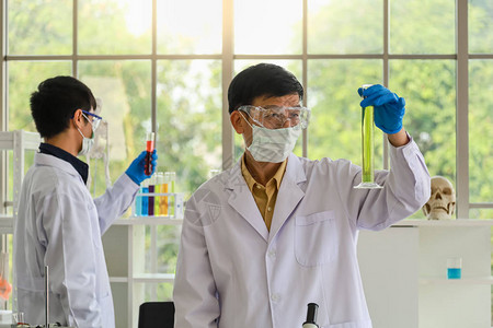 戴着医用颗粒防护面罩实验室眼镜和蓝色橡胶手套的亚洲高级医生的肖像图片
