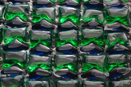 洗衣服的胶囊蓝绿色背景洗衣机用的胶囊图片