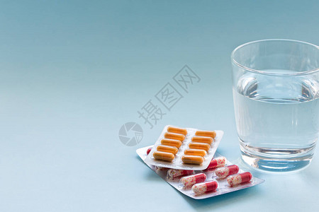 在蓝色表面的清玻璃杯中用水浸泡在充气池中的电池医学概念Fron图片