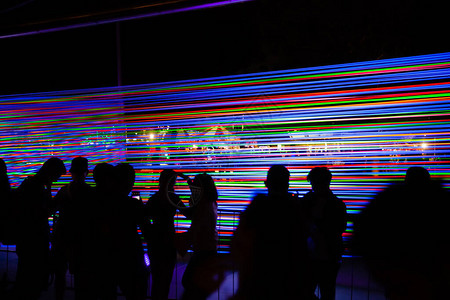 夜间从张紧的霓虹灯电线装置前站在户外的剪影现代展览与技图片