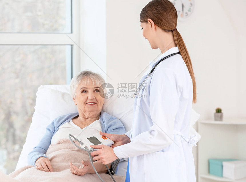 计量诊所内患有帕金森综合症的老年妇女血压的女医图片