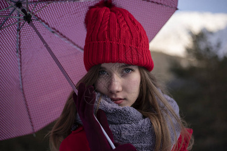 在雪地里戴着红帽子和雨伞的女人图片