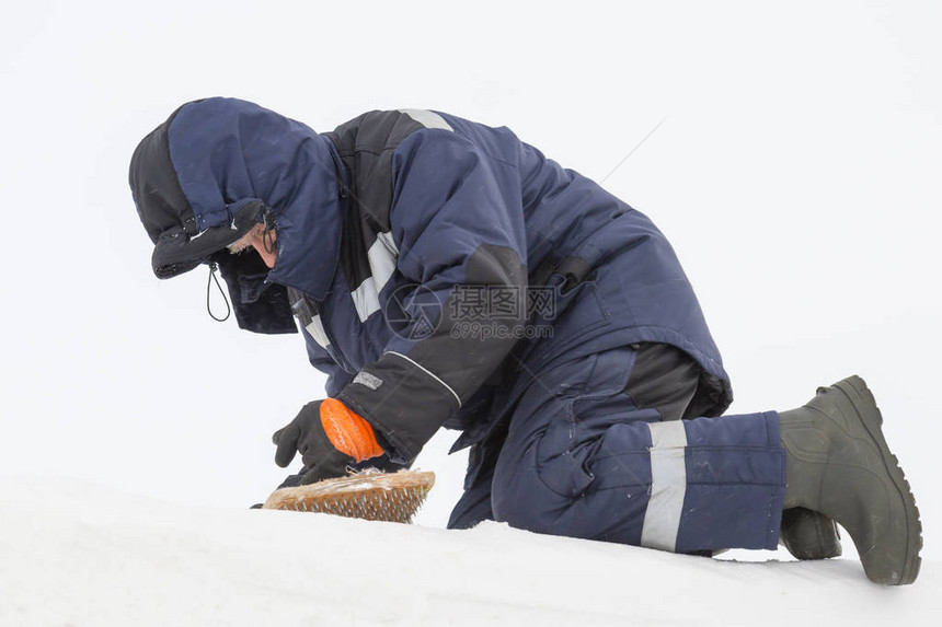 建造者用钢丝刷从雪中清洁冰板图片