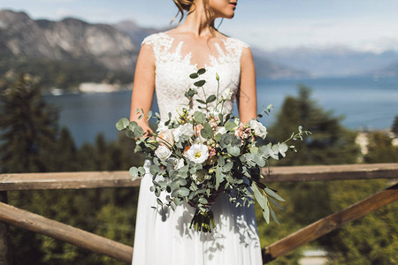 女人手握着盛大的婚礼花束生锈的风格绿玫瑰白玫瑰湖和背景图片