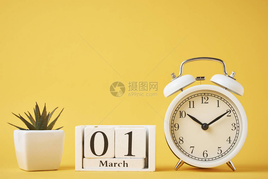 黄色背景和木形日历区块上的白复古闹钟图片