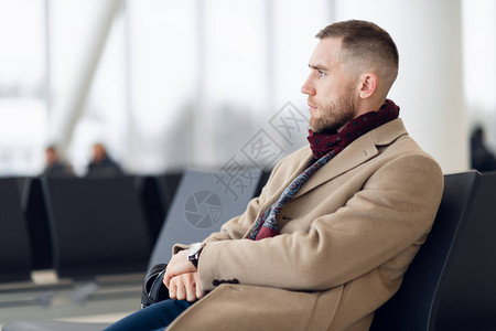商人坐在机场候机室等待航班坐在等候区的机场商务休息室的图片
