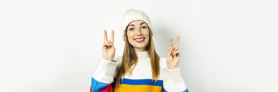 在白色上戴着帽子和毛衣的微笑的年轻女子冬天秋天时尚圣诞节新年惊喜震惊图片