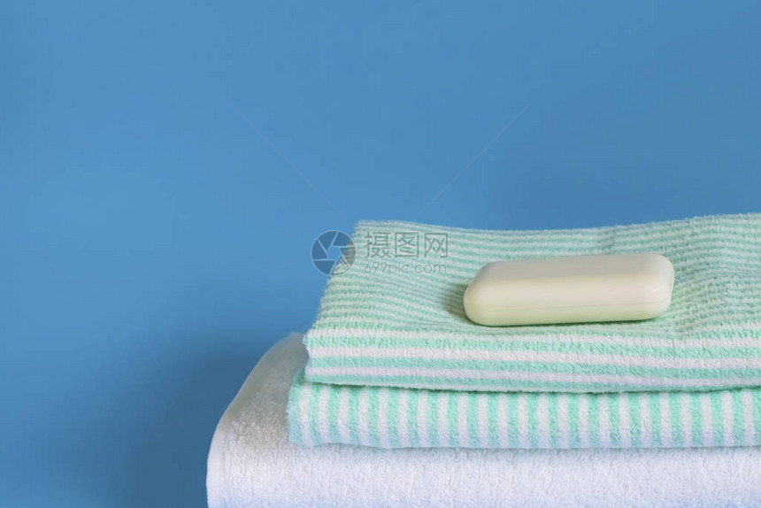 蓝色背景上柔软蓬松的毛巾用于沐浴洗衣和身体护理的肥皂个人卫生用品洗浴用图片