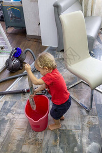 儿童在一桶水中清洗房屋真空和湿抹图片