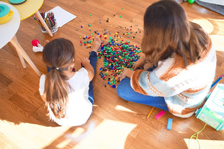 漂亮的老师和幼儿在幼儿园的许多玩具周图片