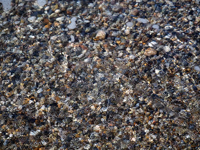 多色鹅卵石在清澈的水中水面布满了淡的涟漪宁图片