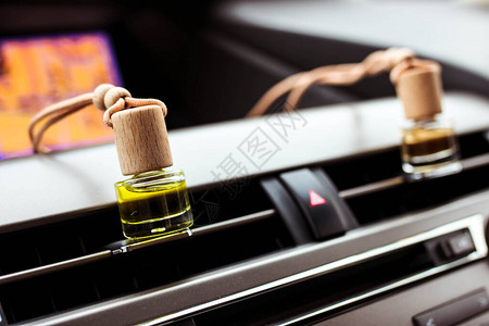 车内两个香水清新剂瓶子在铬汽车面板上图片