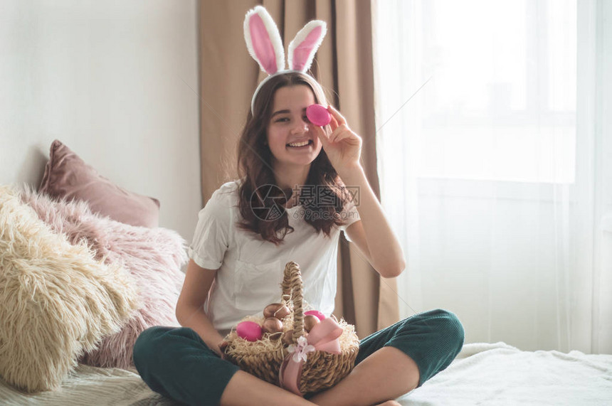 有复活节耳朵和柳条复活节篮子的少女用鸡蛋在客厅的床上闭了眼睛情绪图片