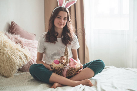 有复活节耳朵和柳条复活节篮子的少女在客厅的床上情绪图片