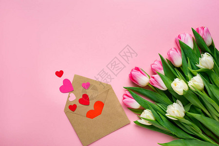粉红色表面的郁金香花束旁有纸红心图片